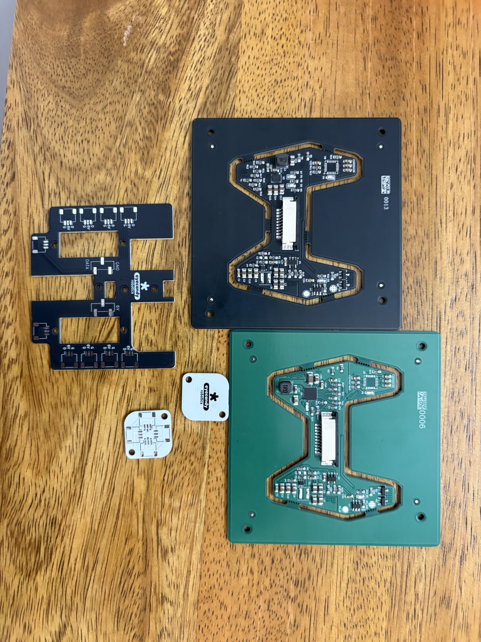 Four bare PCBs laid out on a wooden table